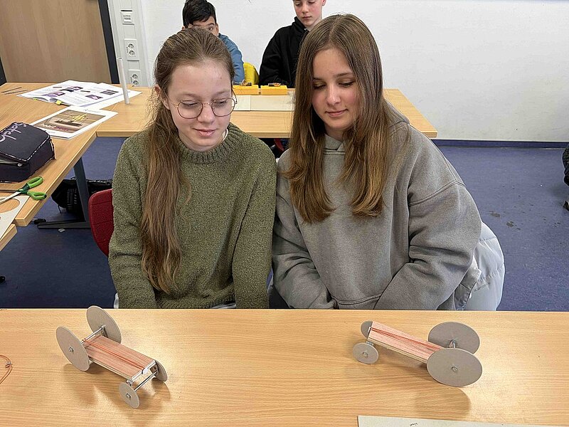 Noelia Schamul und Svea Hermann (7G2) betrachten ihre selbst gebastelten Autos. Noch fehlen die Antriebsteile.